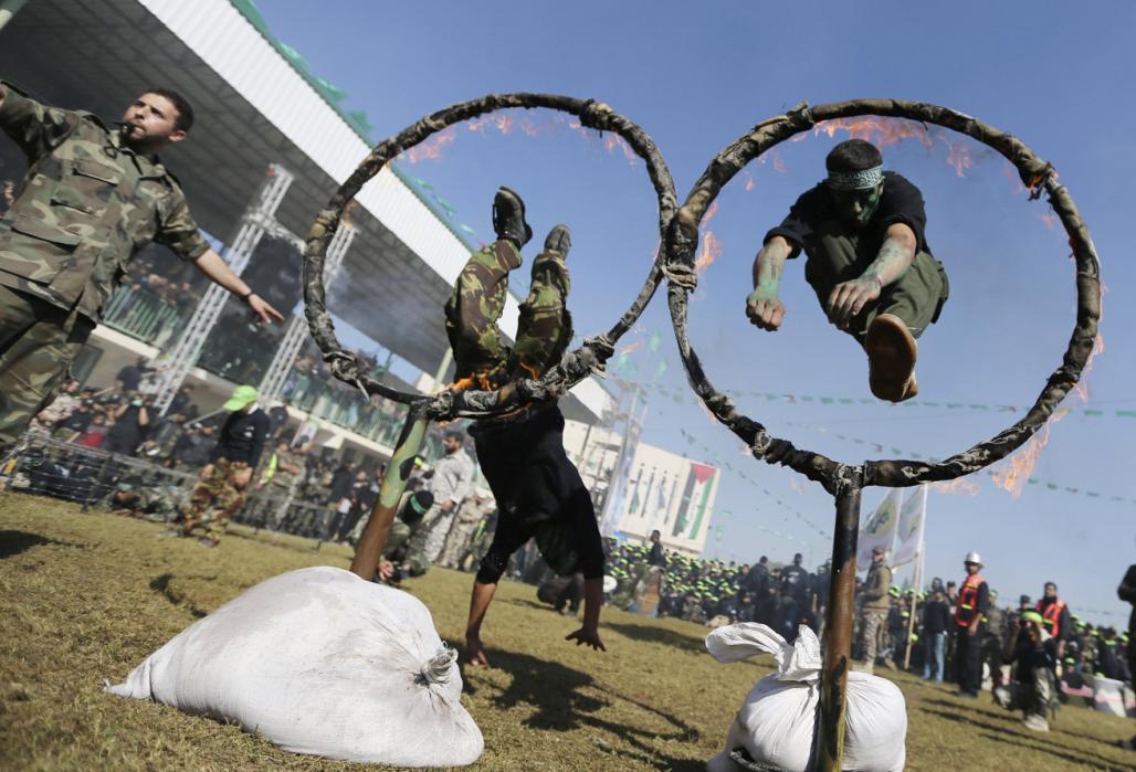 Palestinian youths jump through rings of fire during a military-style graduation ceremony after being trained at one of the Hamas-run Liberation Camps, in Khan Younis